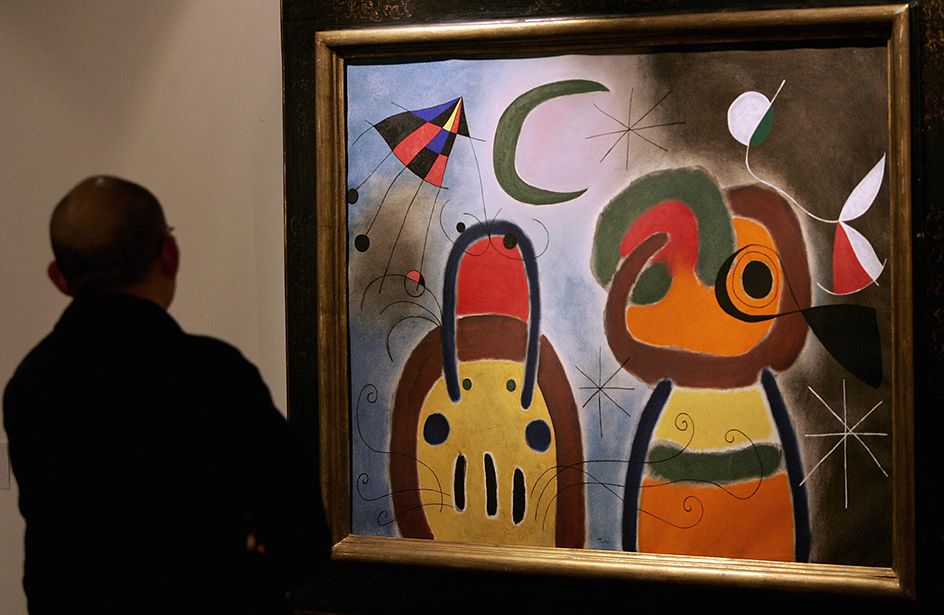 A man views a painting by Joan Miró