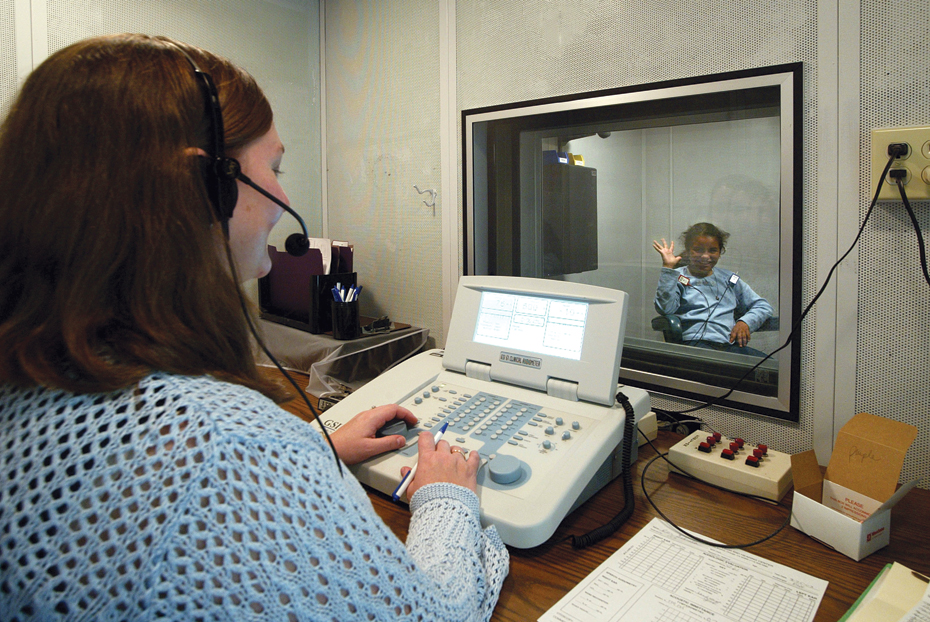 An audiologist checks a child's hearing