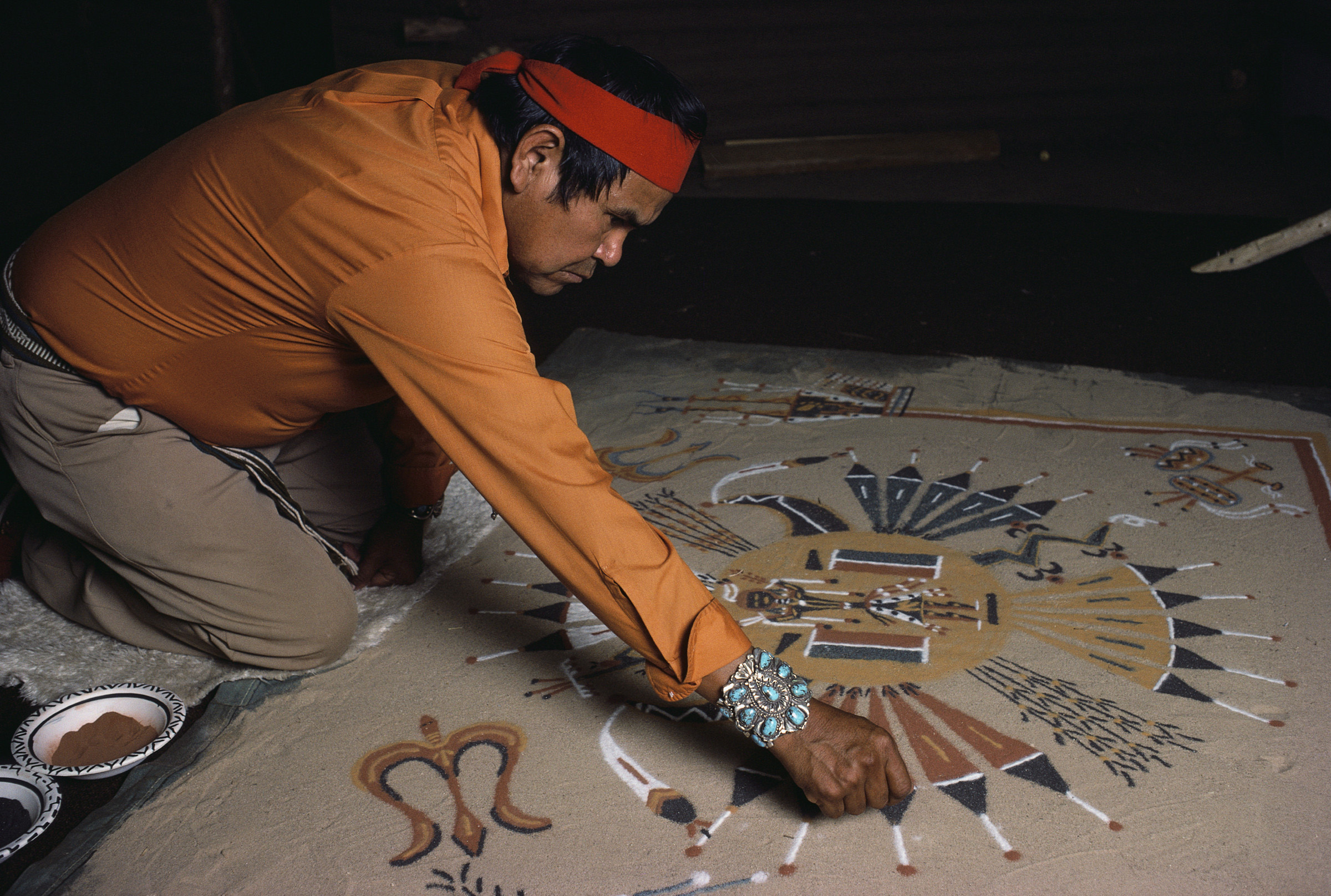 A Navajo man makes a sand painting