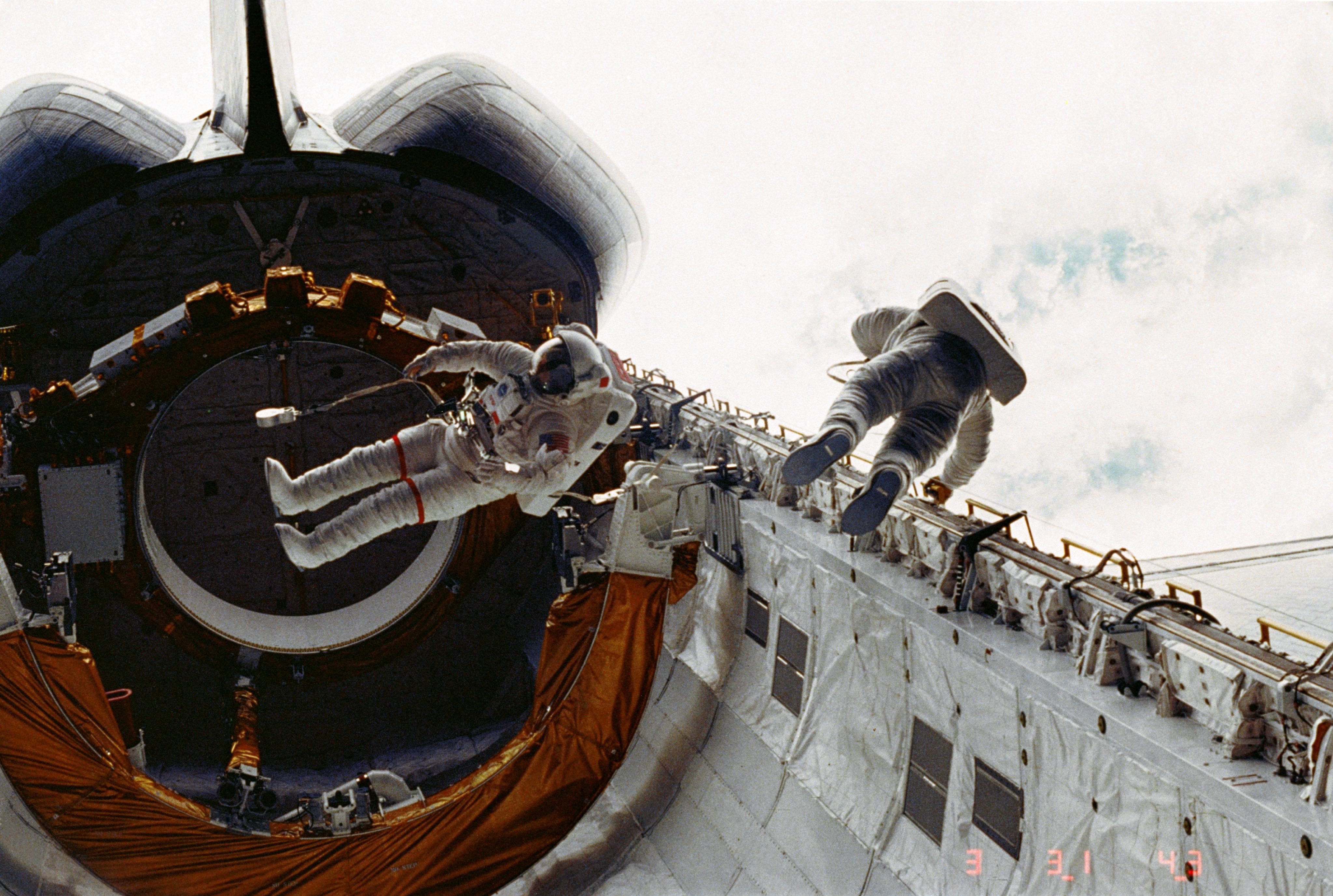 Two spacewalking astronauts float in the open cargo bay of the U.S. space shuttle Challenger