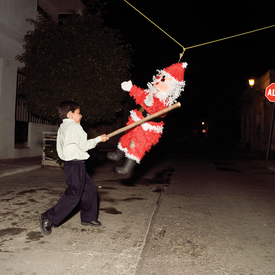 Boy hitting Christmas pinata, Mexico