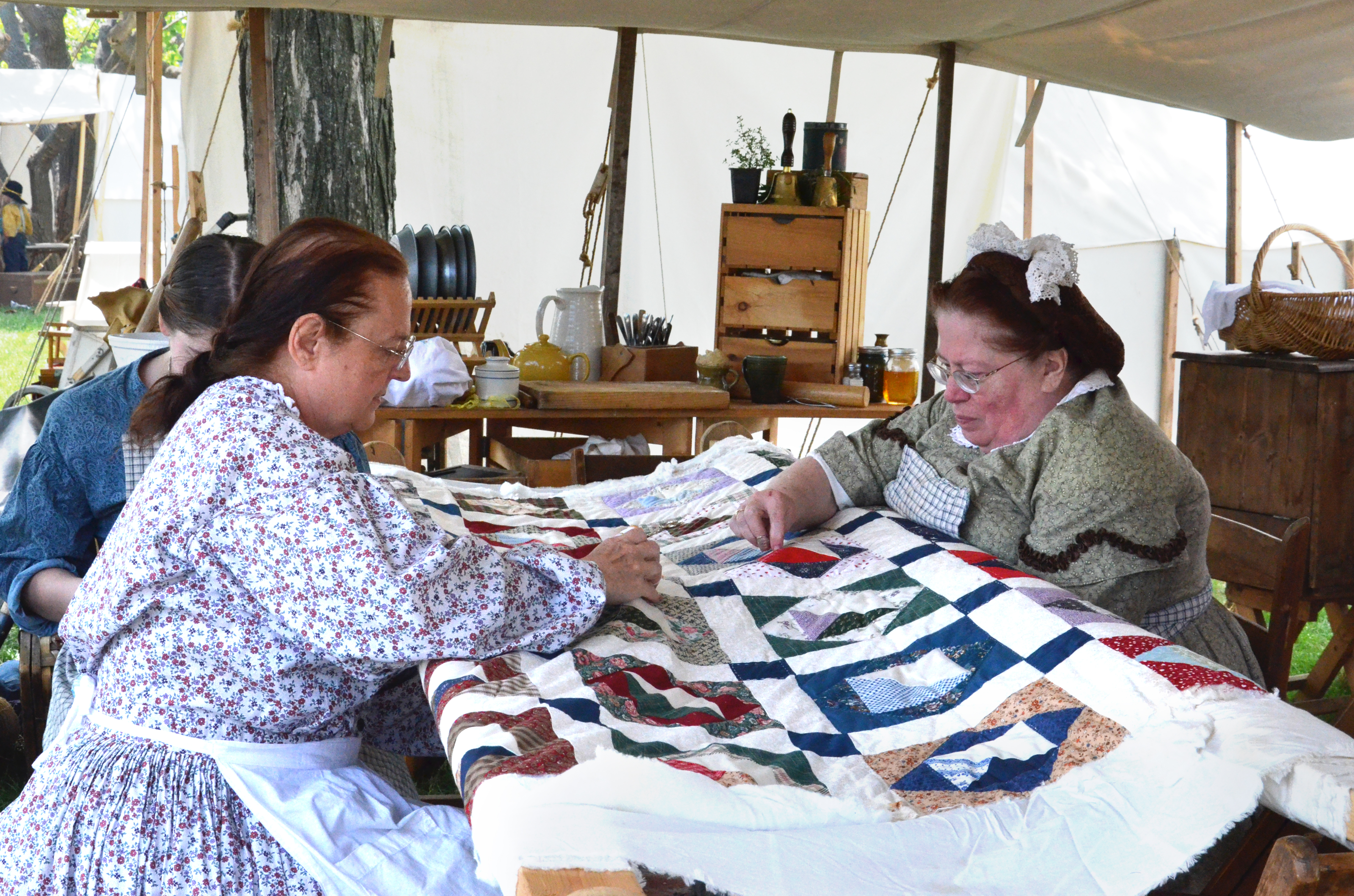 Historical reenactors sewing a quilt