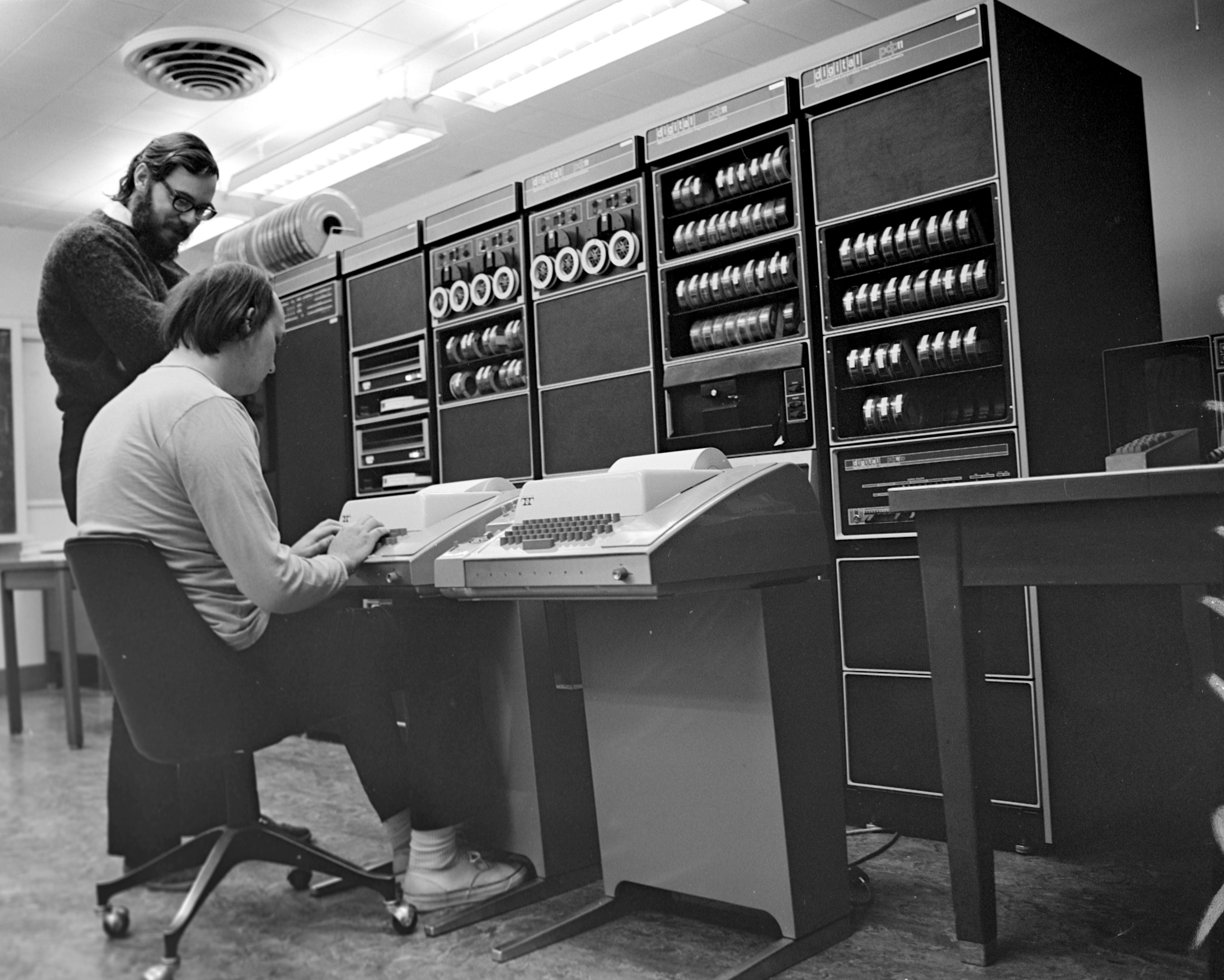 American computer scientist Dennis Ritchie standing at an early computer