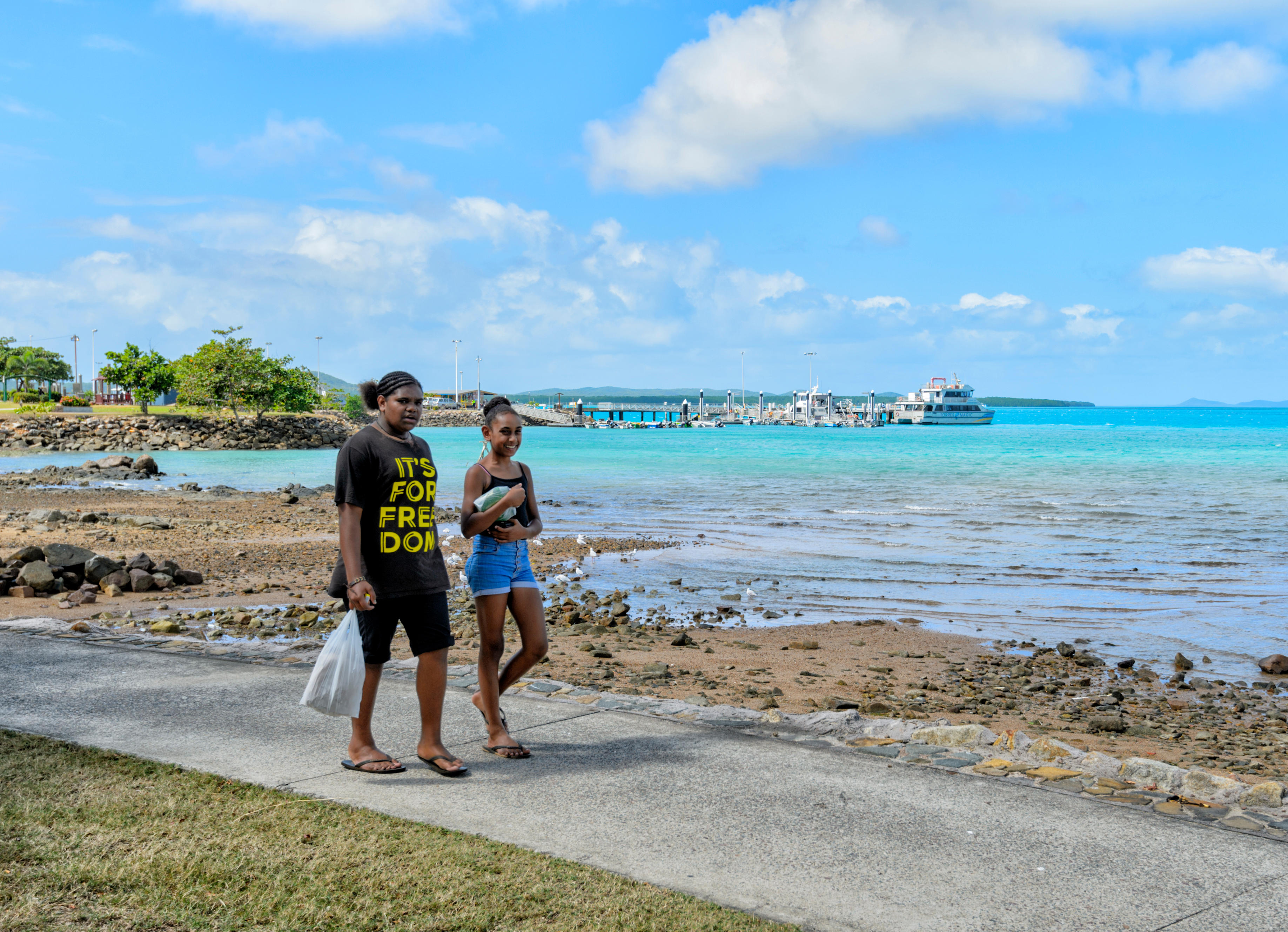 Young Torres Strait Islander women stroll along the shore of Thursday Island in northern Queensland, Australia