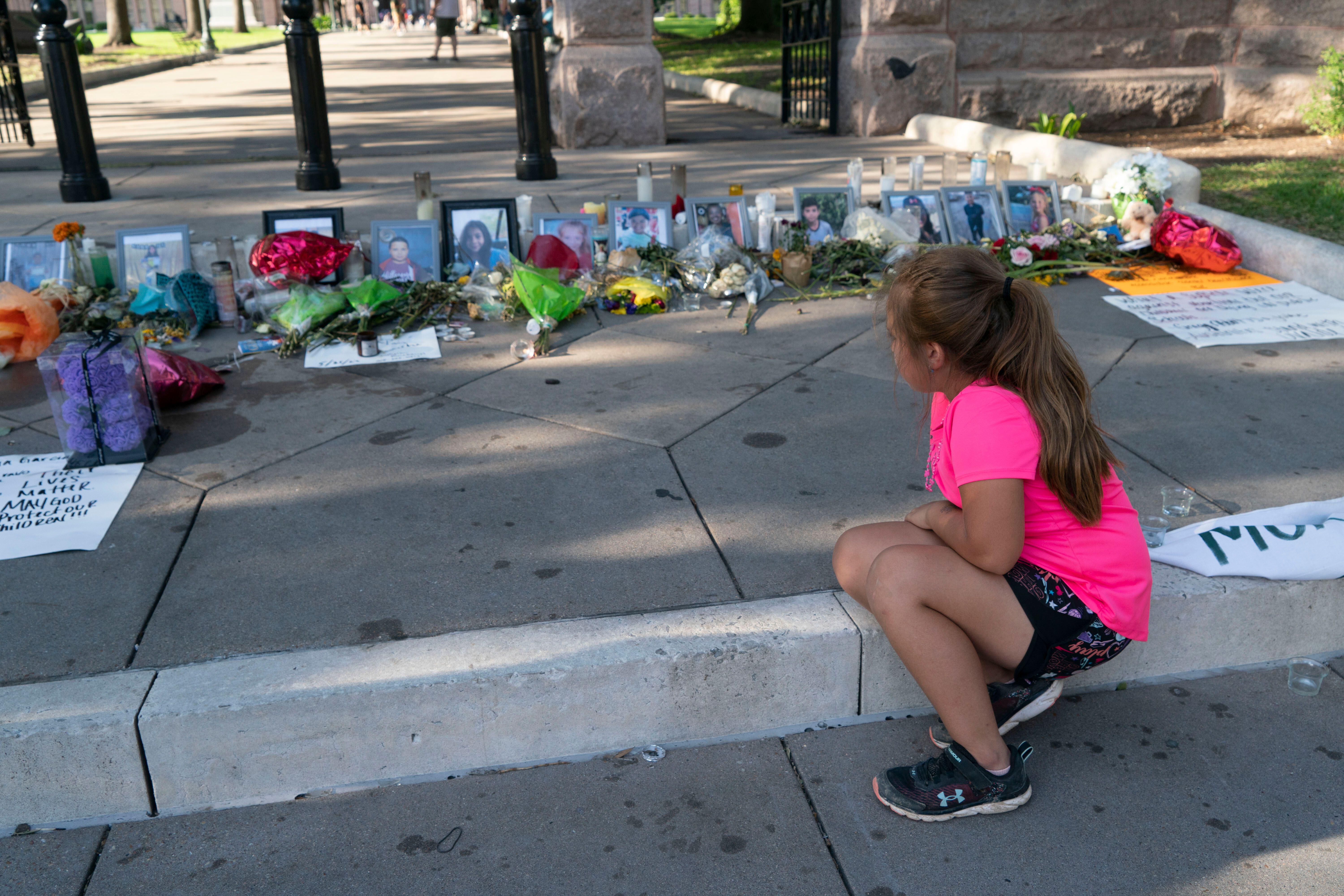 A student sits at a memorial for the victims of the Robb Elementary School shooting